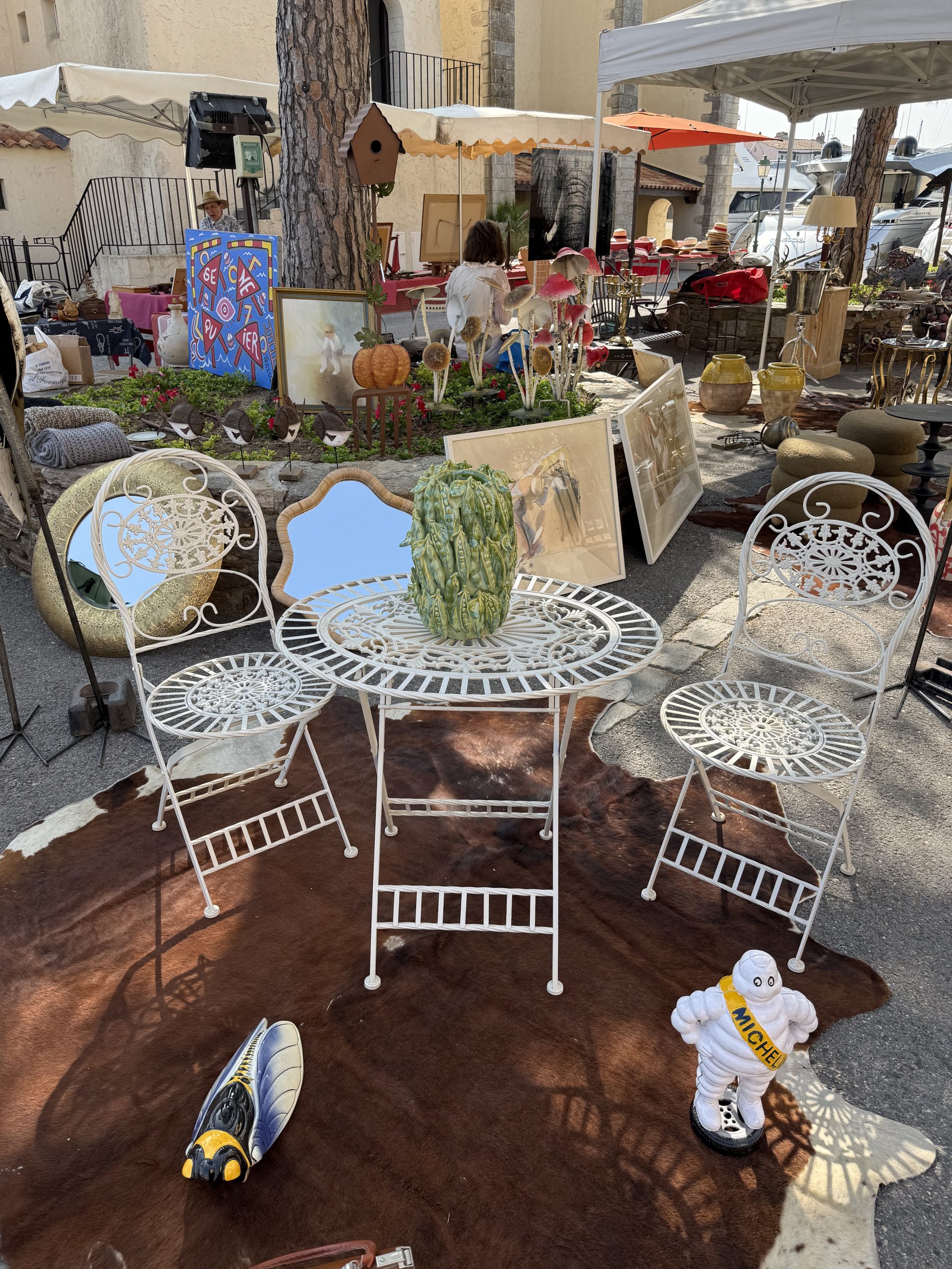 Salon de jardin en fer forgé blanc, table ronde et deux chaises, sur tapis en peau