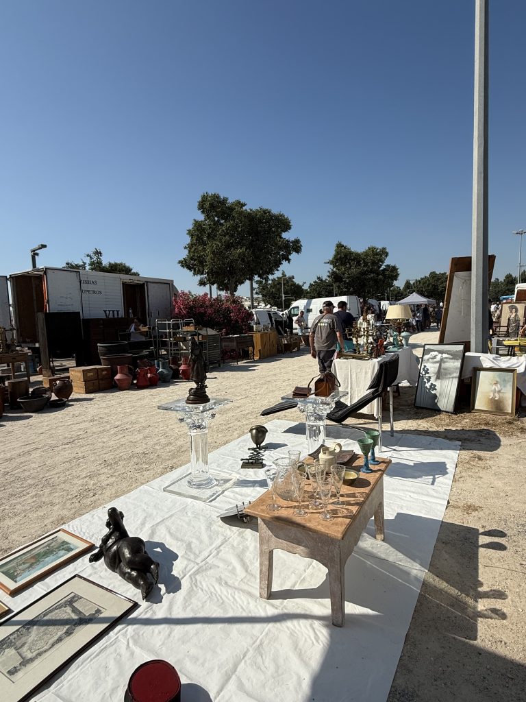 Déballage de brocante en plein air : verrerie, chandeliers, bronze animalier et gravures encadrées