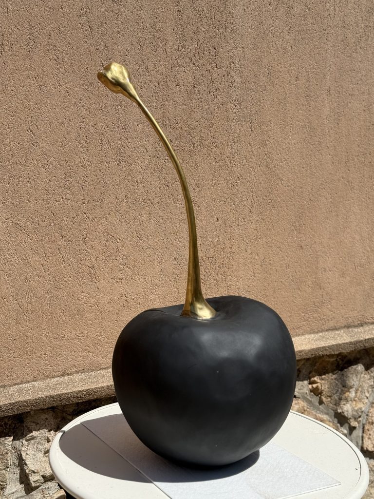 Sculpture décorative d'une cerise noire mate à la tige dorée