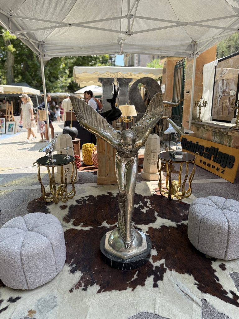 Grande sculpture chromée d'une figure ailée sur tapis en peau, entourée de poufs et de lanternes dorées